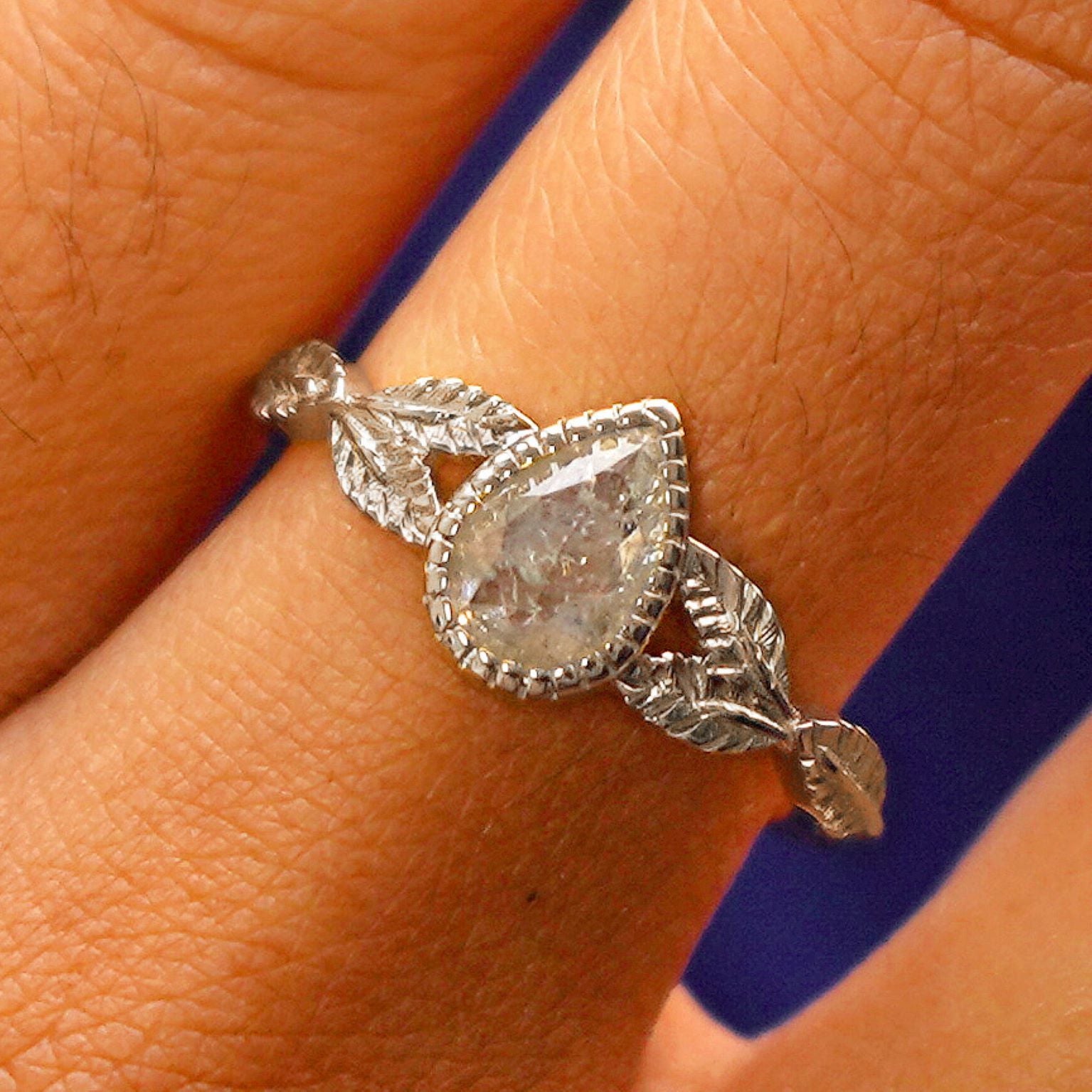 Close up view of a model's fingers wearing a 14k white gold Pear Salt and Pepper Diamond Leaves Ring