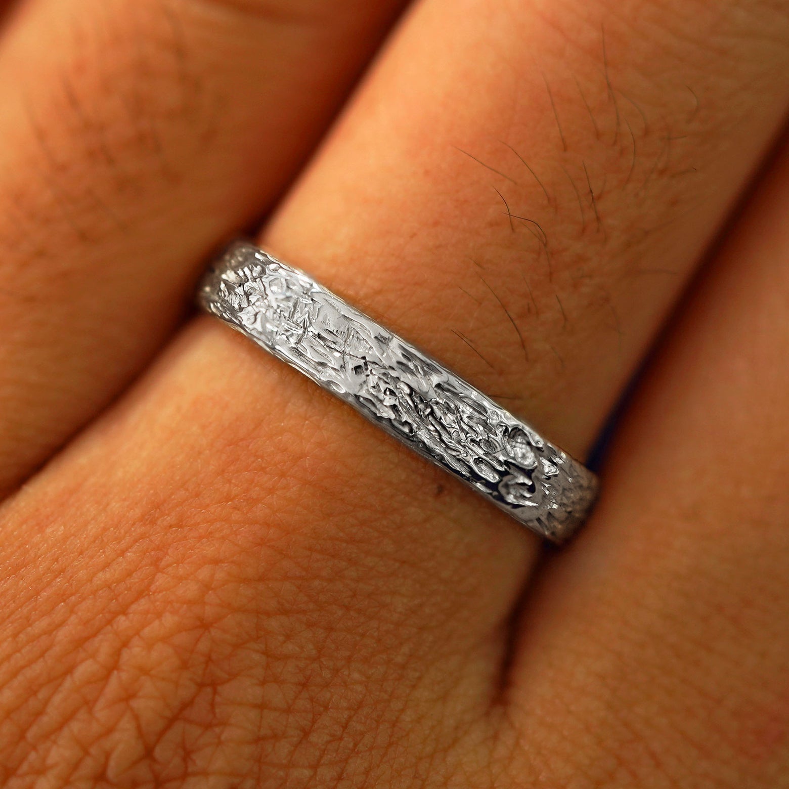 Close up view of a model's fingers wearing a 14k white gold Raw Band