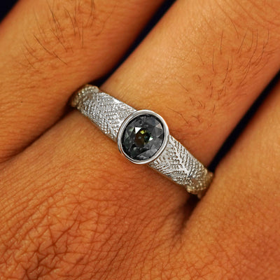 Close up view of a model's fingers wearing a 14k white gold Dark Green Sapphire Pine Ring