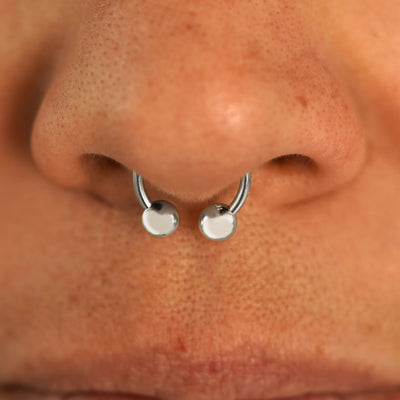 Close up view of a model's nose wearing a 14k white gold Small Horseshoe in a septum piercing