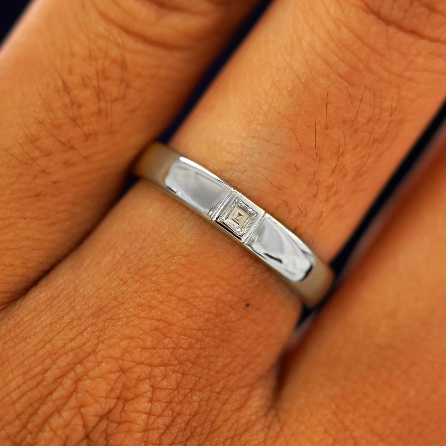 Close up view of a model's fingers wearing a 14k white gold Square Carre Cut Diamond Band