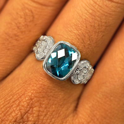 Close up view of a model's fingers wearing a white gold London blue topaz Royalty Ring