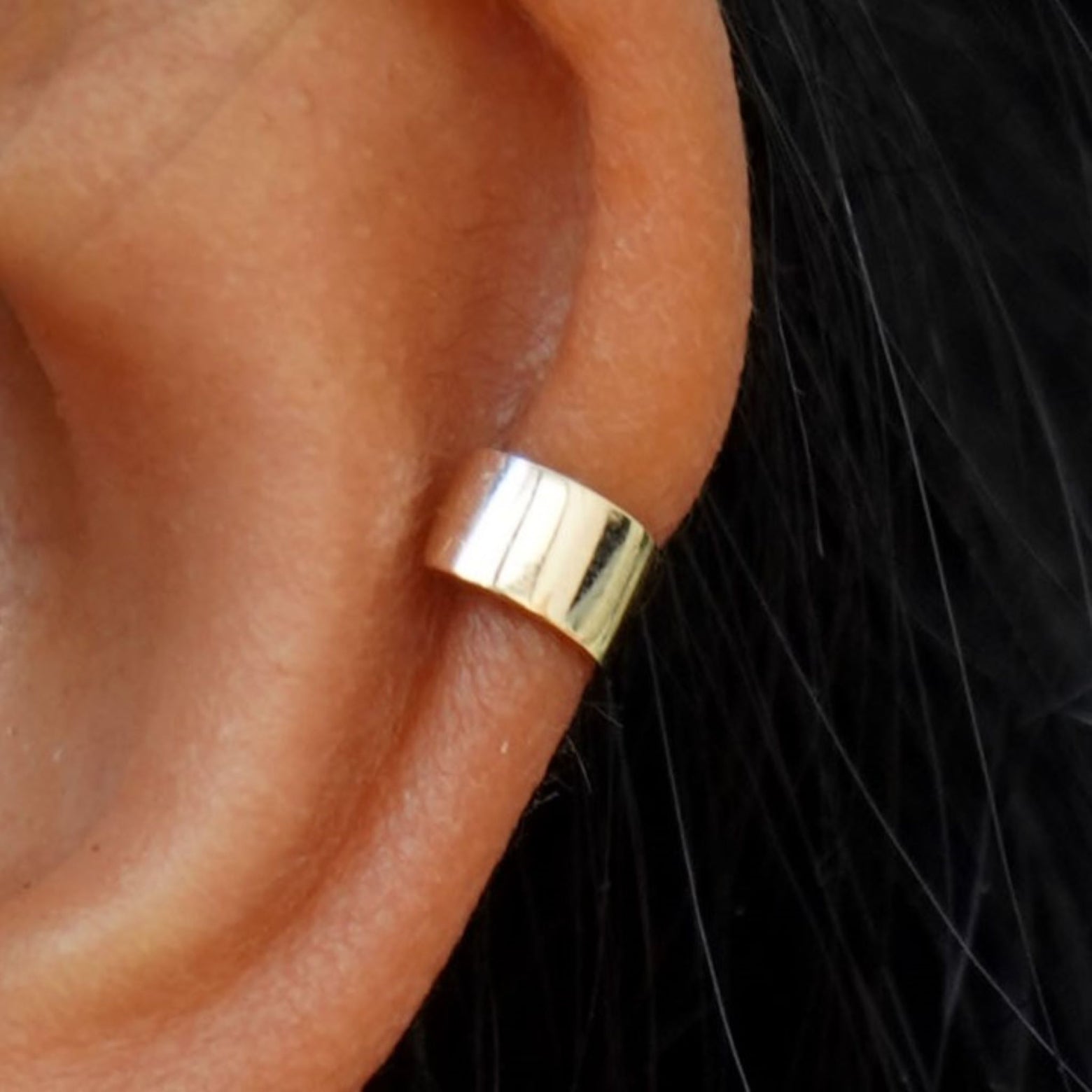 Close up view of a model's ear wearing a yellow gold Thick Cuff