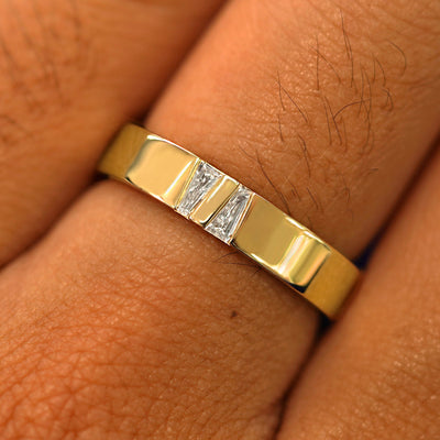 Close up view of a model's hand wearing a solid yellow gold Double Baguette Diamond Band