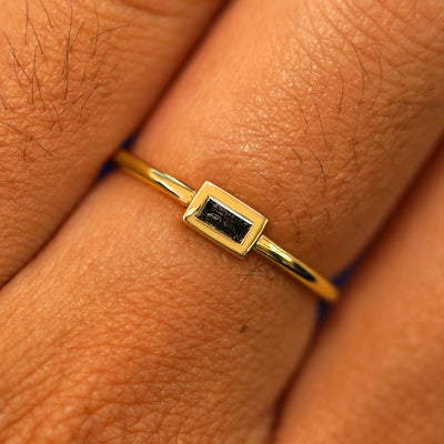 Close up view of a model's fingers wearing a 14k yellow gold Baguette Salt and Pepper Diamond Ring