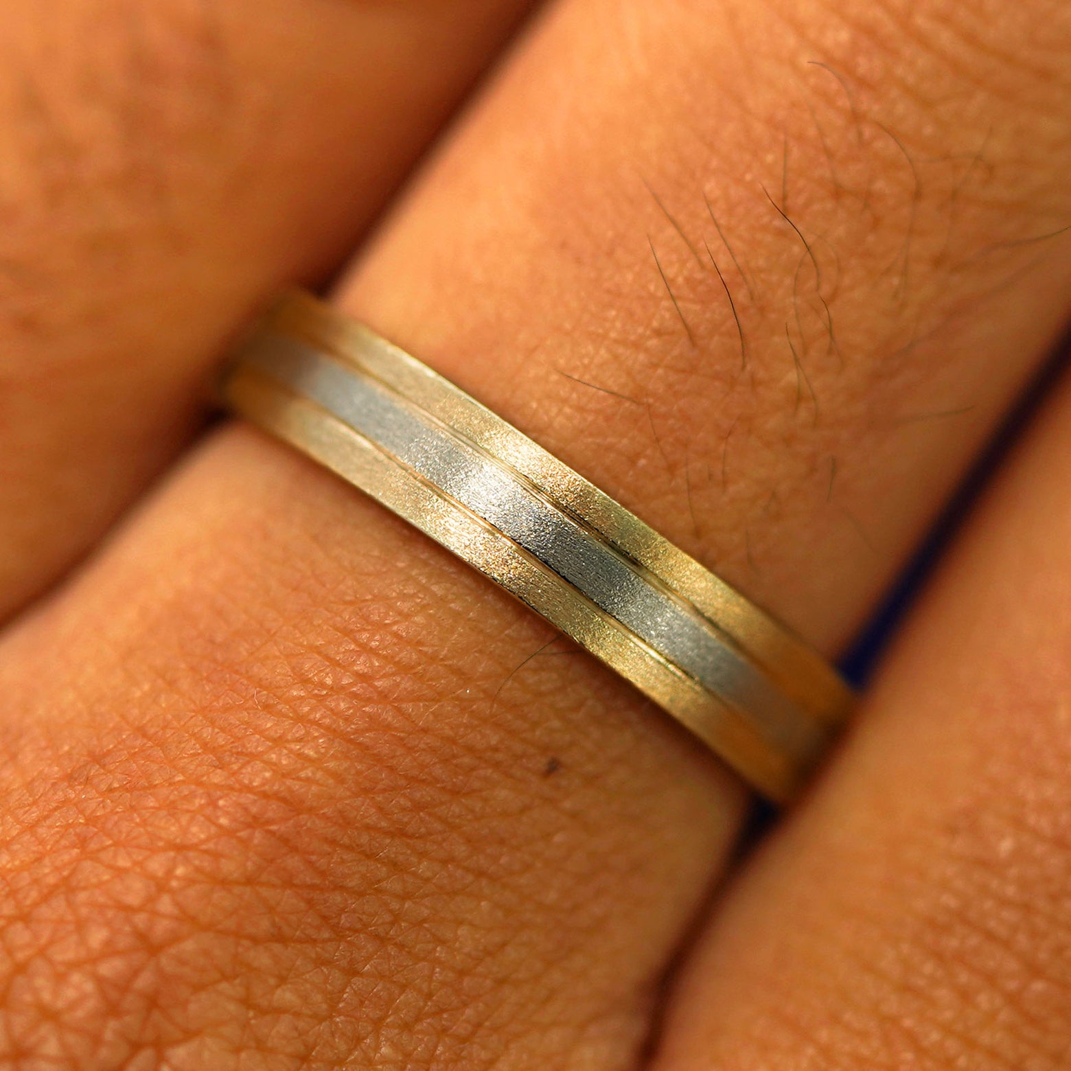 Close up view of a model's fingers wearing a 14k solid yellow gold with champagne gold Inlay Band