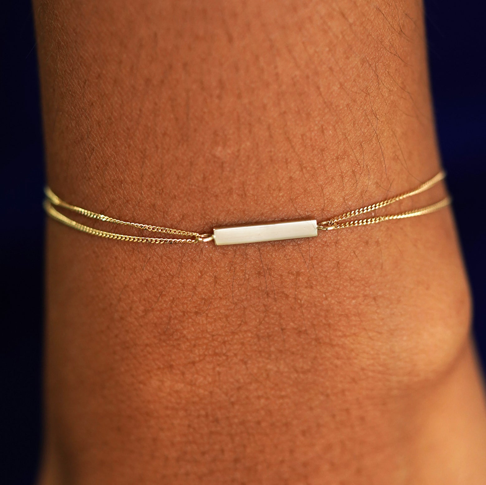 A model's wrist wearing a solid yellow gold Bar Bracelet