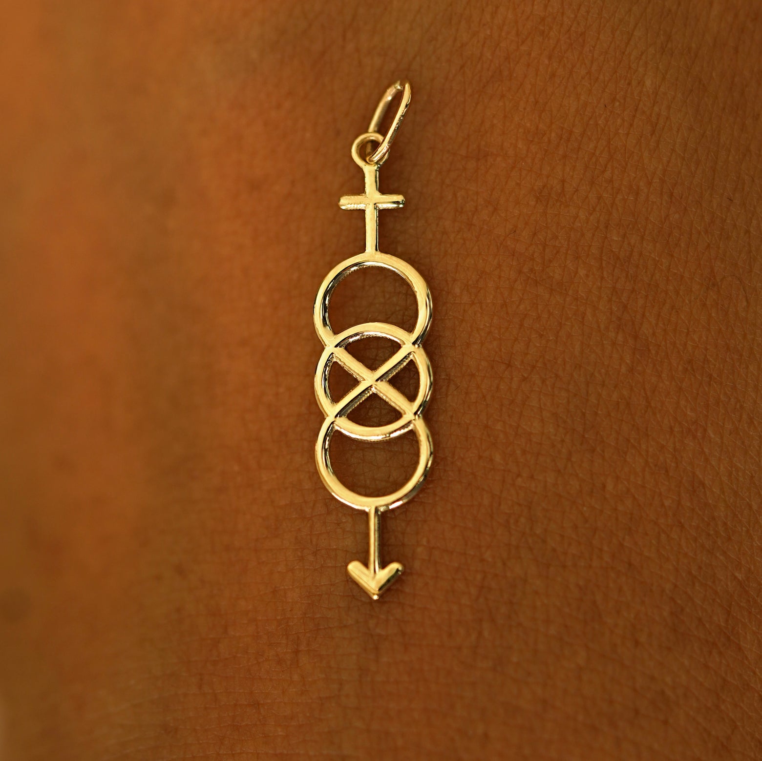 A solid 14k yellow gold Bisexual Symbol Charm resting on the back of a model's hand