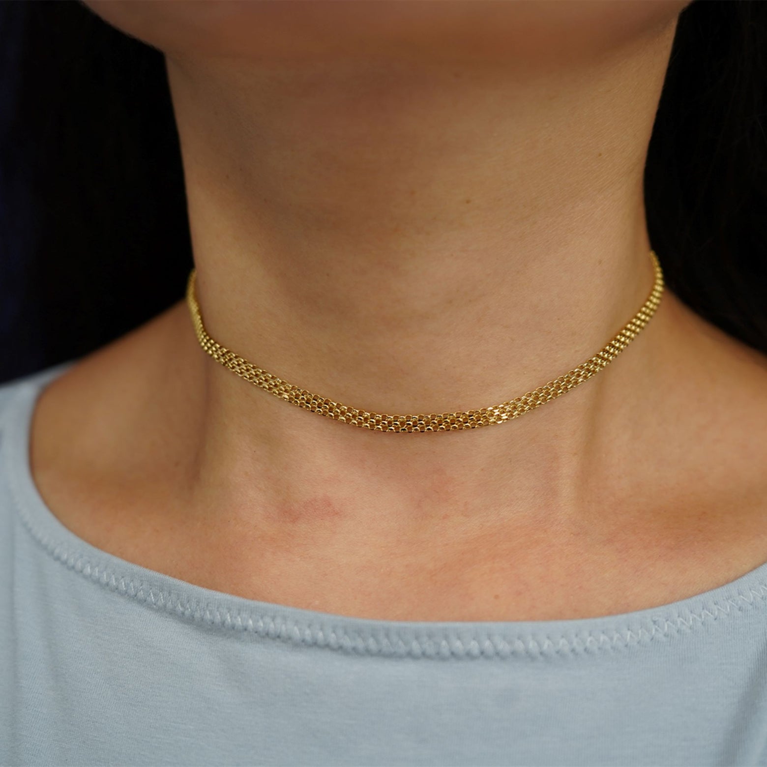 A model's neck wearing a solid 14k yellow gold Bismarck Chain as a choker necklace