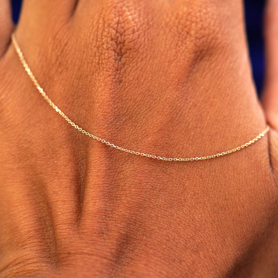 A solid gold Cable Chain resting on the back of a model's hand