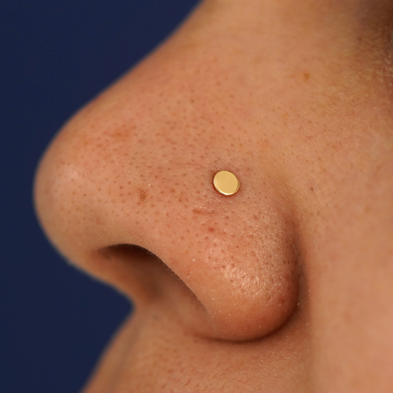 Close up view of a model's nose wearing a yellow gold Circle Nose Stud