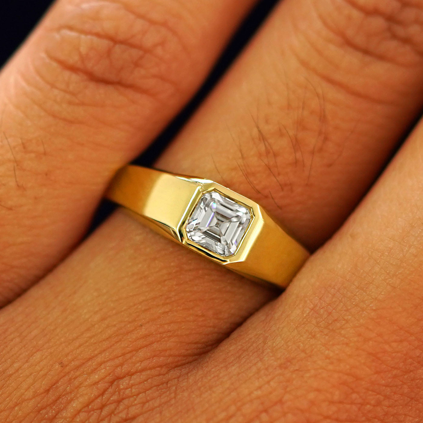 Close up view of a model's fingers wearing a  yellow gold white Asscher Moissanite Signet Ring