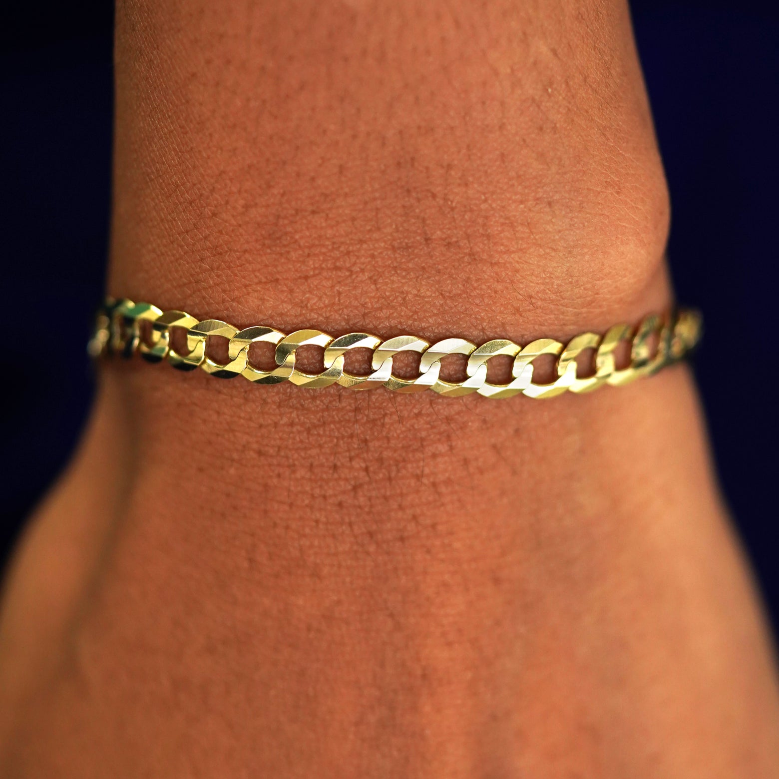 A model's wrist wearing a yellow gold Curb Chain Bracelet