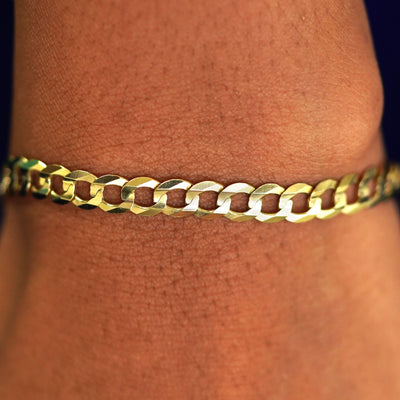 Close up view of a model's wrist wearing a yellow gold Curb Chain Bracelet