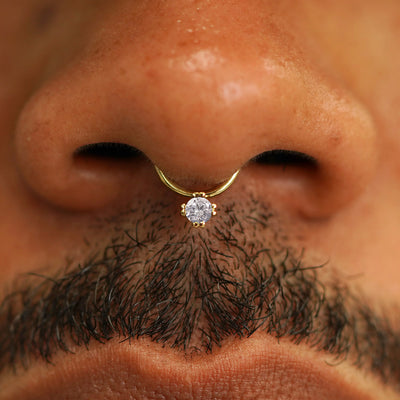 Close up view of a model's face wearing a 14k solid yellow gold Diamond Septum