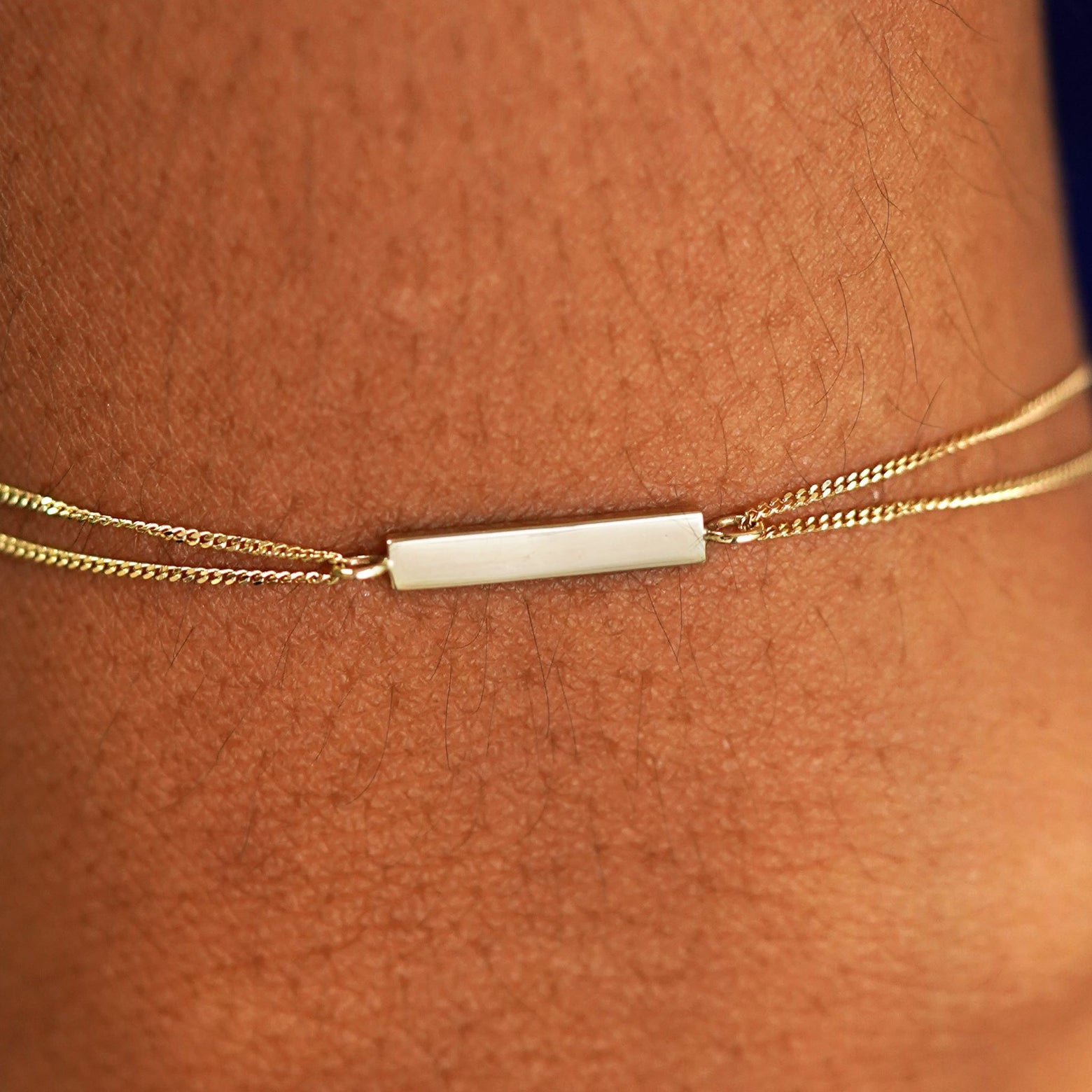 Close up view of a model's wrist wearing a solid yellow gold Bar Bracelet