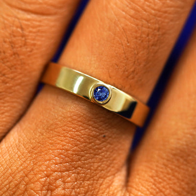 Close up view of a model's fingers wearing a 14k yellow gold sapphire Gemstone Industrial Band