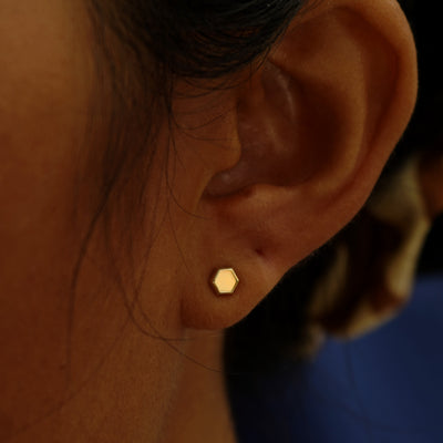 A model's ear wearing a 14k yellow gold Hexagon Earring