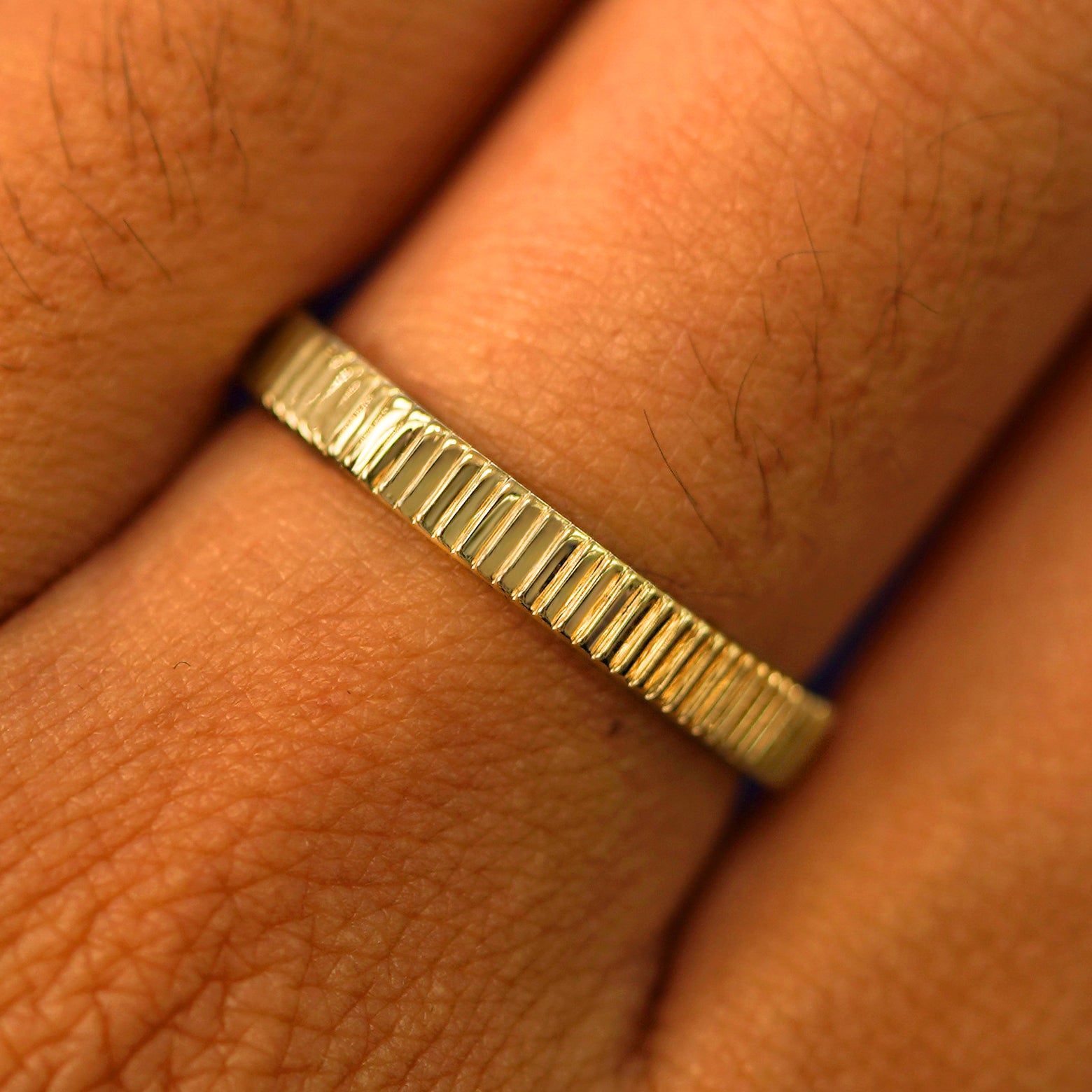 Close up view of a model's fingers wearing a 14k yellow gold Edge Band