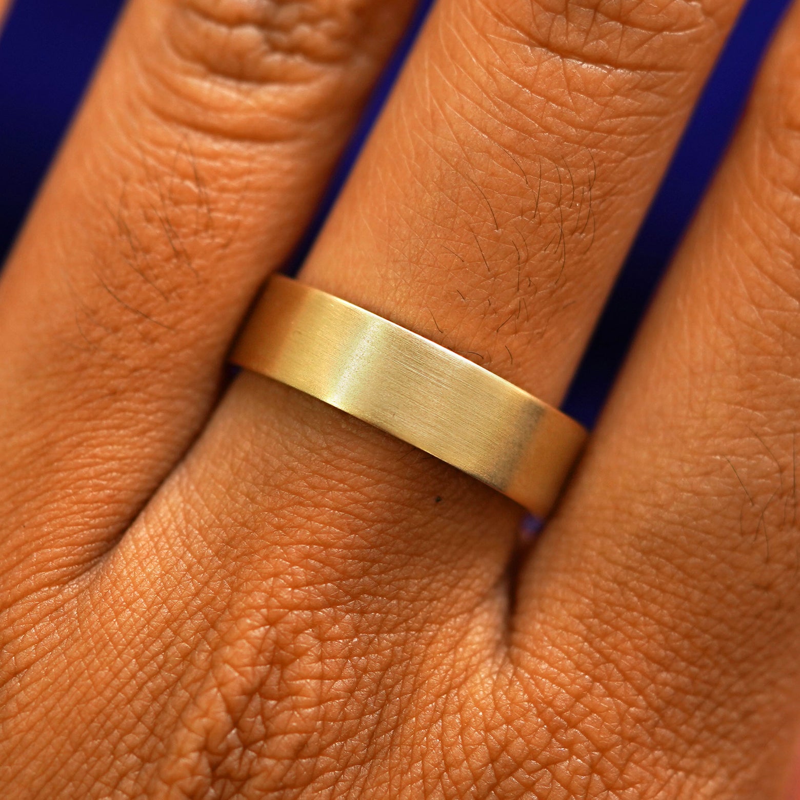 Close up view of a model's fingers wearing a 14k yellow gold Industrial Matte Band