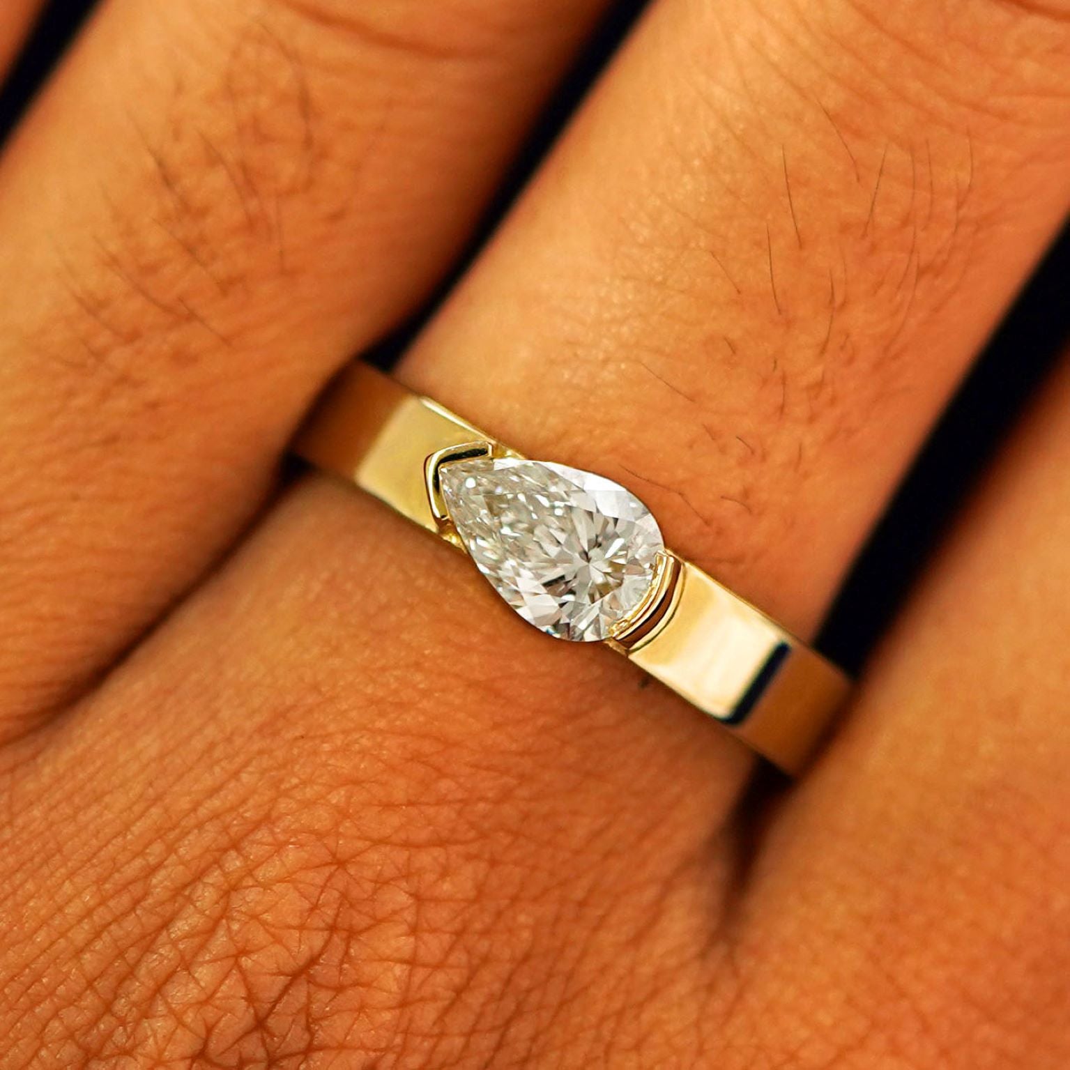 Close up view of a model's fingers wearing a 14k yellow gold Lab Diamond Pear Ring