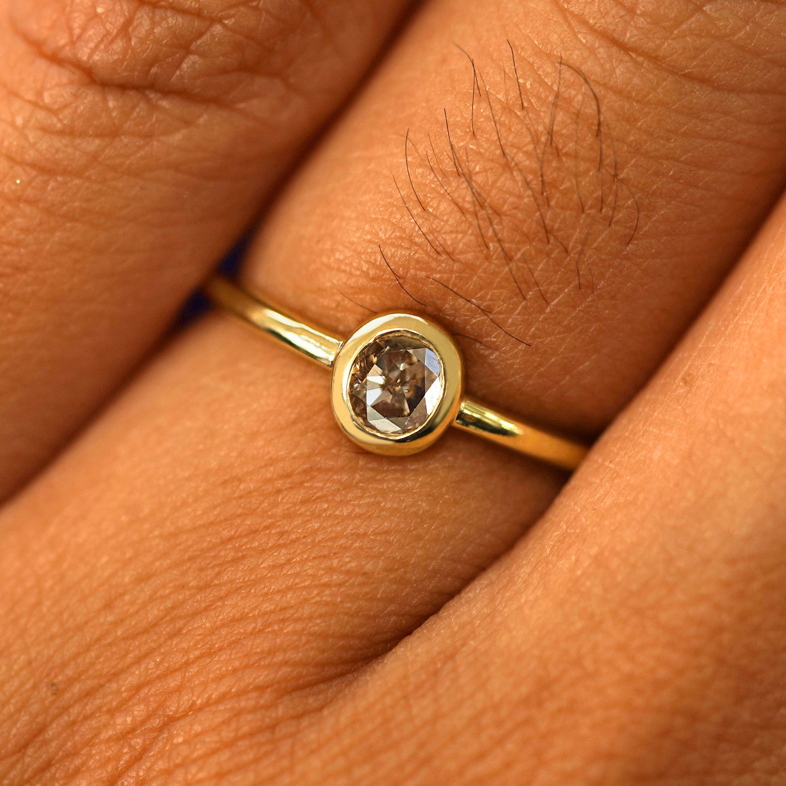 Close up view of a model's fingers wearing a 14k yellow gold Oval Champagne Diamond Ring