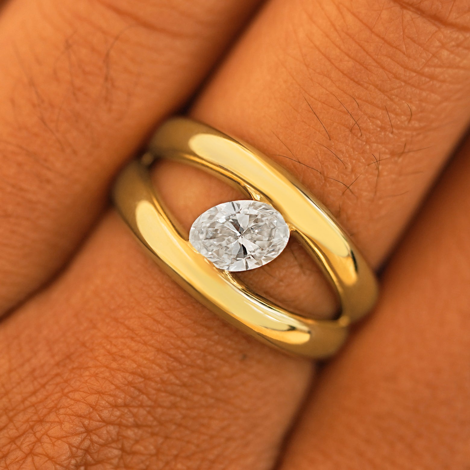 Close up view of a model's fingers wearing a 14k yellow gold Oval Lab Diamond Tension Ring