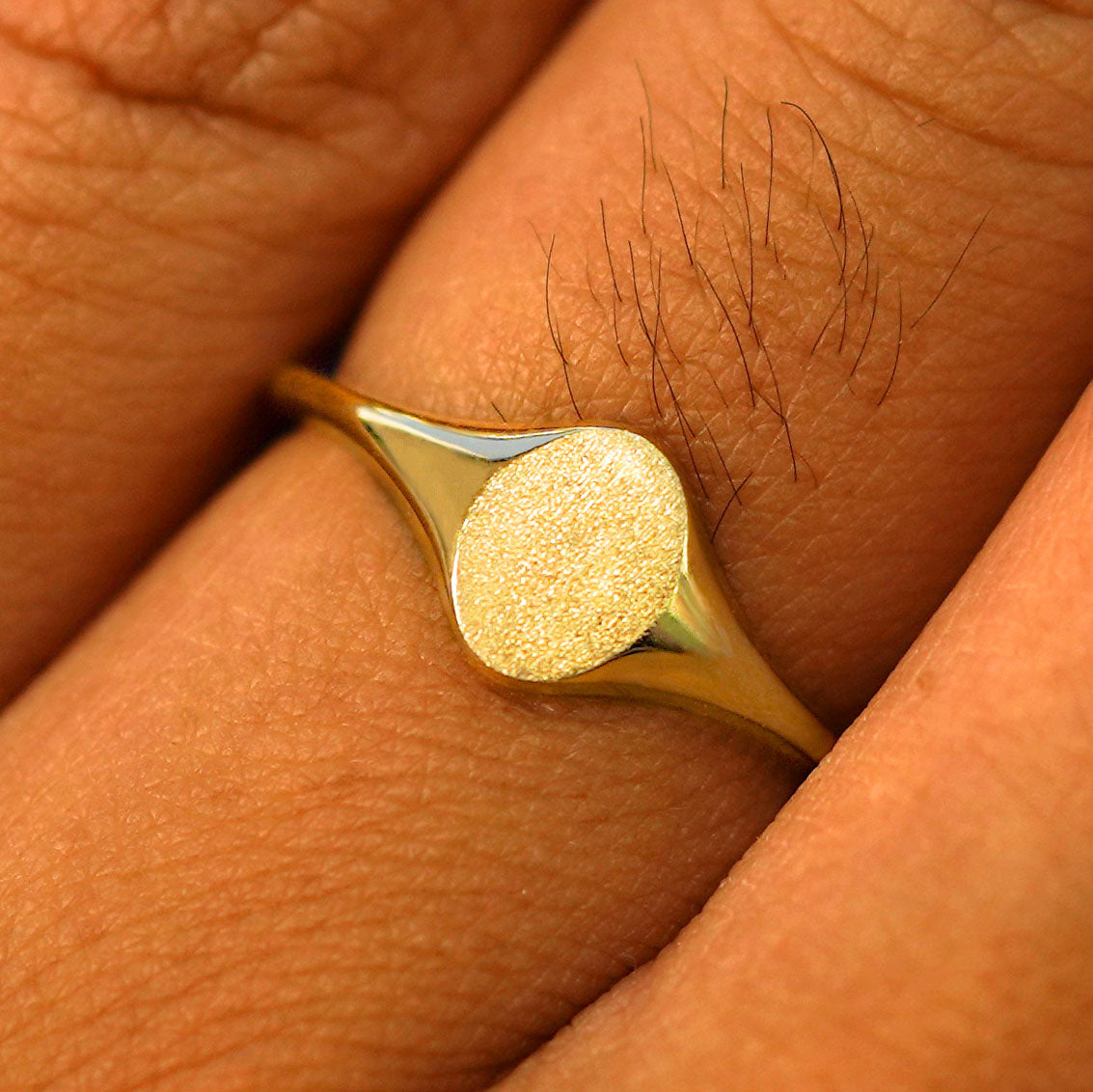 Close up view of a model's fingers wearing a 14k yellow gold Oval Signet Ring