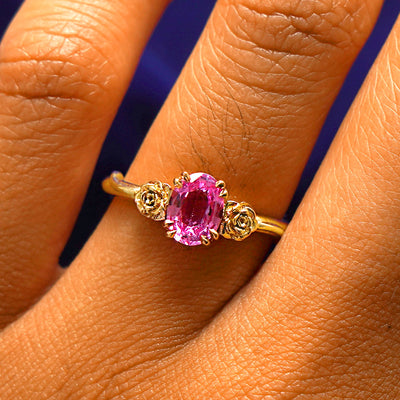 Close up view of a model's fingers wearing a 14k yellow gold Pink Sapphire Roses Ring