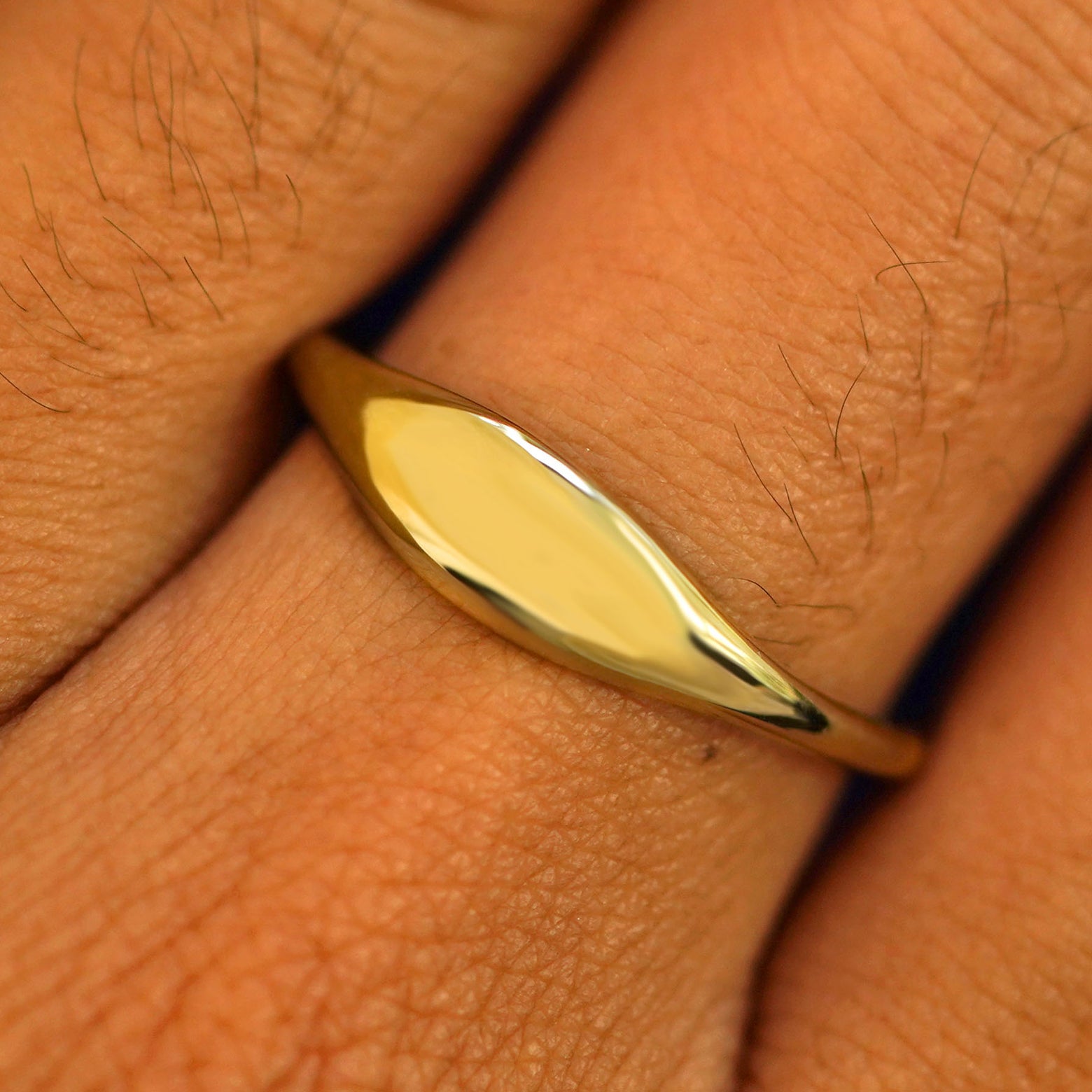 Close up view of a model's fingers wearing a 14k yellow gold Puffy Elongated Signet Ring