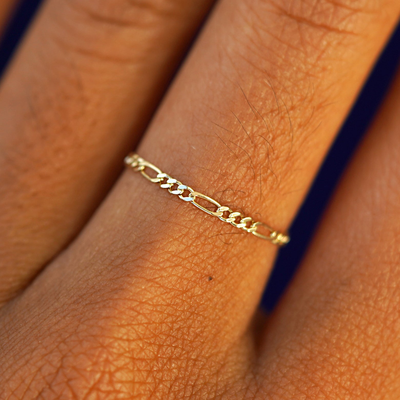 Close up view of a model's hand wearing a solid yellow gold Figaro Ring