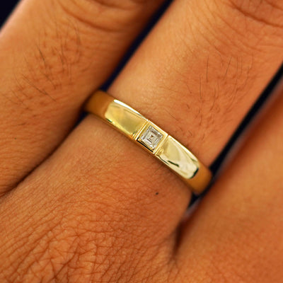 Close up view of a model's fingers wearing a 14k yellow gold Square Carre Cut Diamond Band