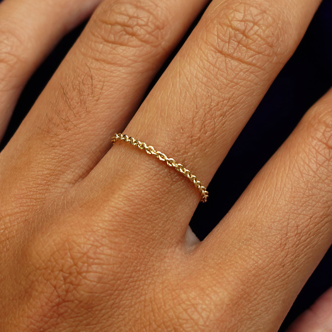 Close up view of a model's hand wearing a solid yellow gold Thick Cable Ring