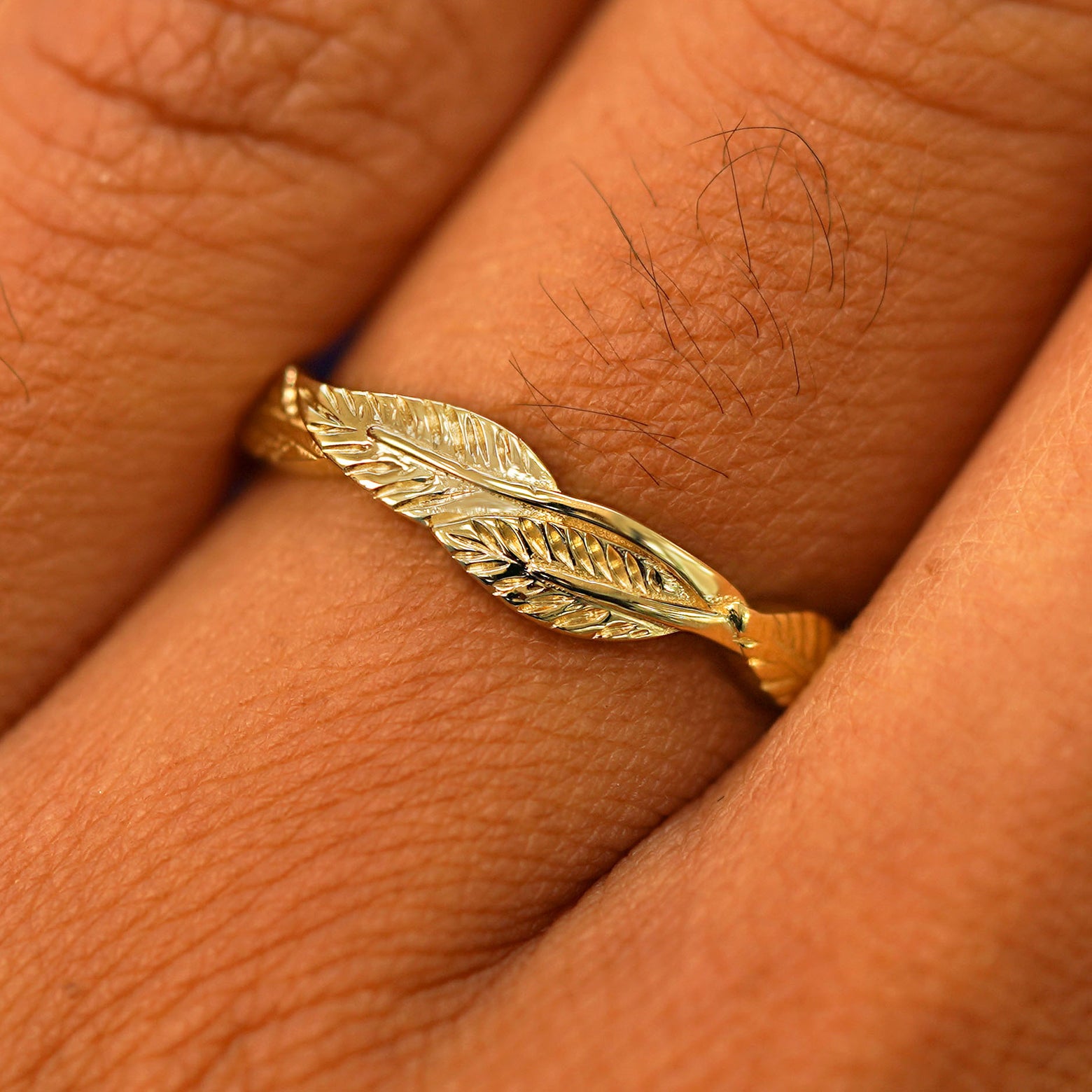 Close up view of a model's fingers wearing a 14k yellow gold Thick Leaves Band