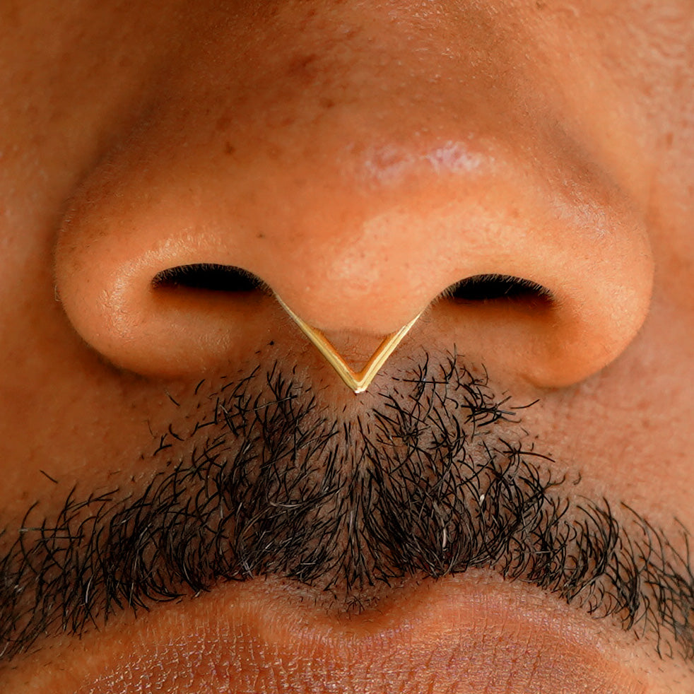 Close up view of a model's face wearing a 14k solid yellow gold Triangle Septum