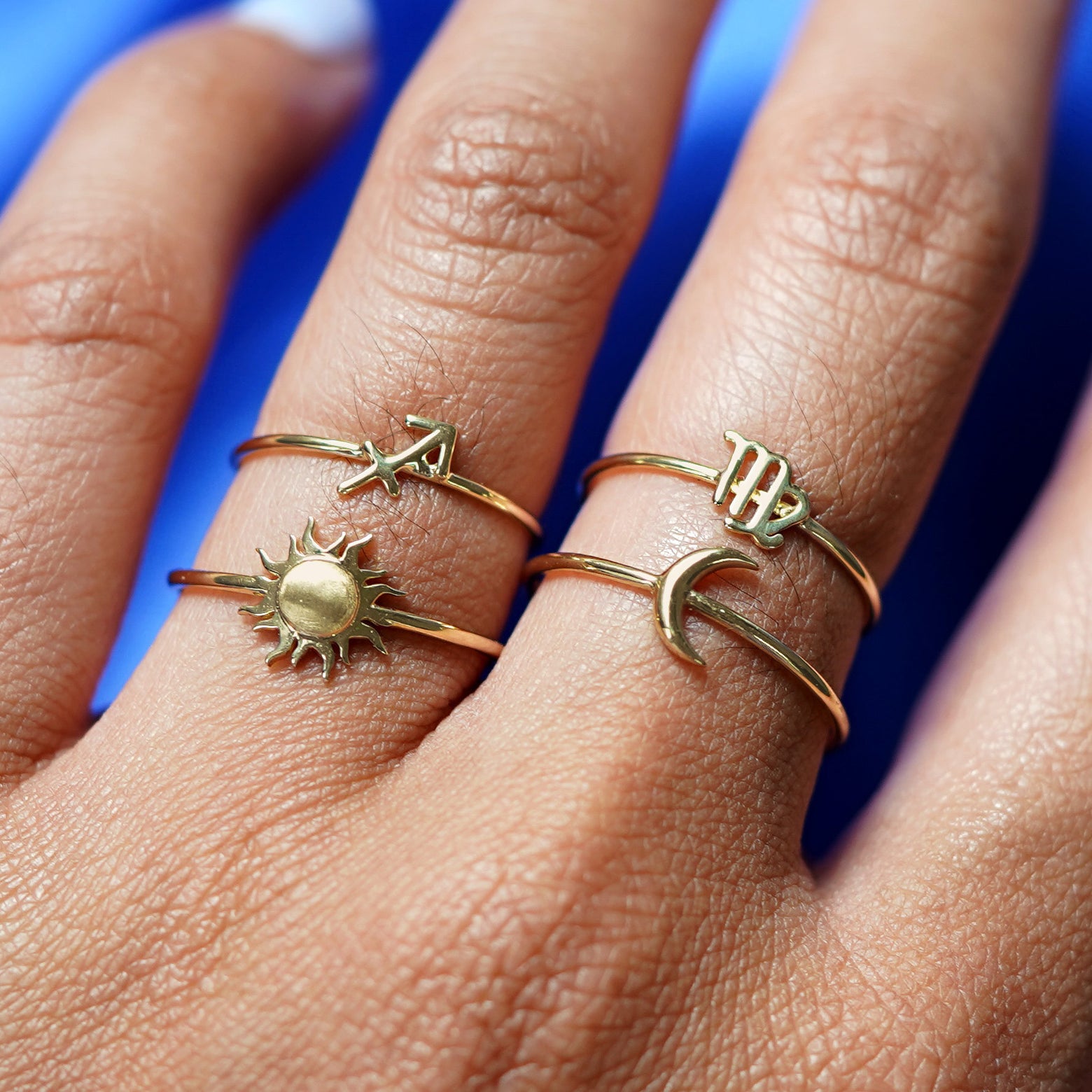 Close up view of a model's hand wearing yellow gold Sagittarius and Virgo Horoscope Rings, a Sun Ring and a Moon Ring