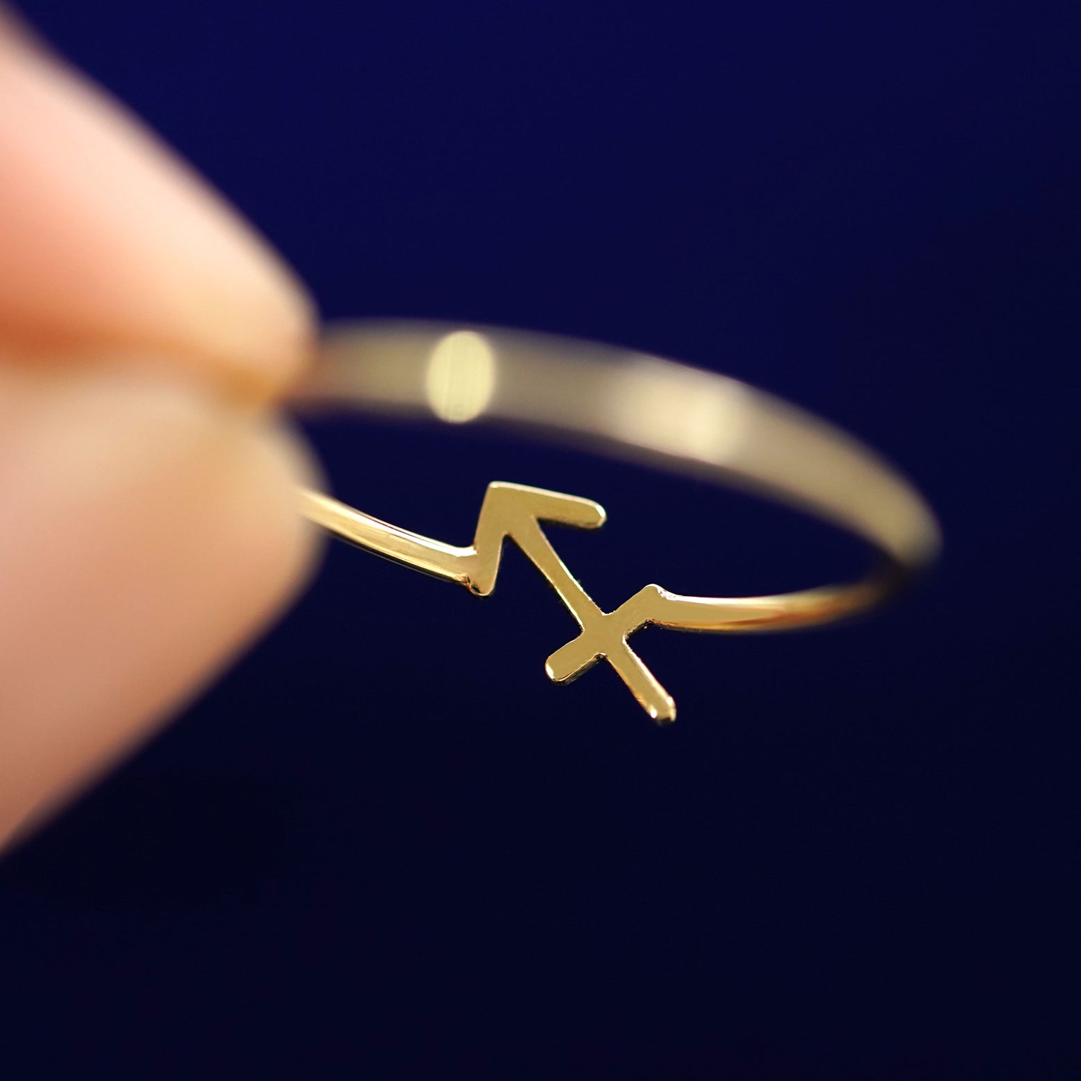 A model holding a Sagittarius Horoscope Ring between two fingers to to show the underside view