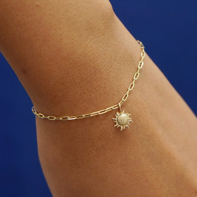 Close up view of a model's wrist wearing a yellow gold Sun Charm on a Butch Chain Bracelet