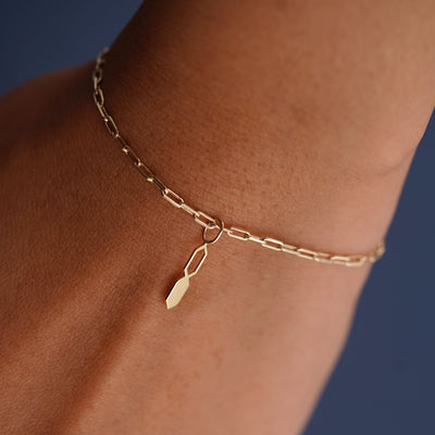 Close up view of a model's wrist wearing a yellow gold Tanlah Charm on a Butch Bracelet