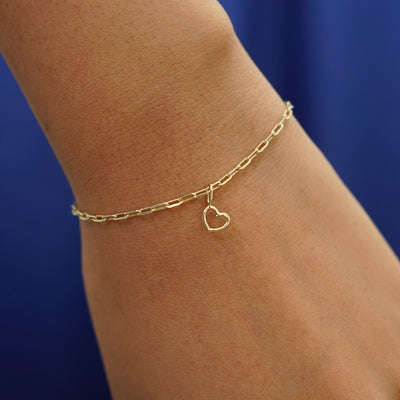 Close up view of a model's wrist wearing a yellow gold Heart Charm on a Butch Bracelet