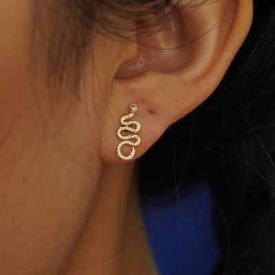 Close up view of a model's ear wearing a yellow gold Snake Flat Back Earring