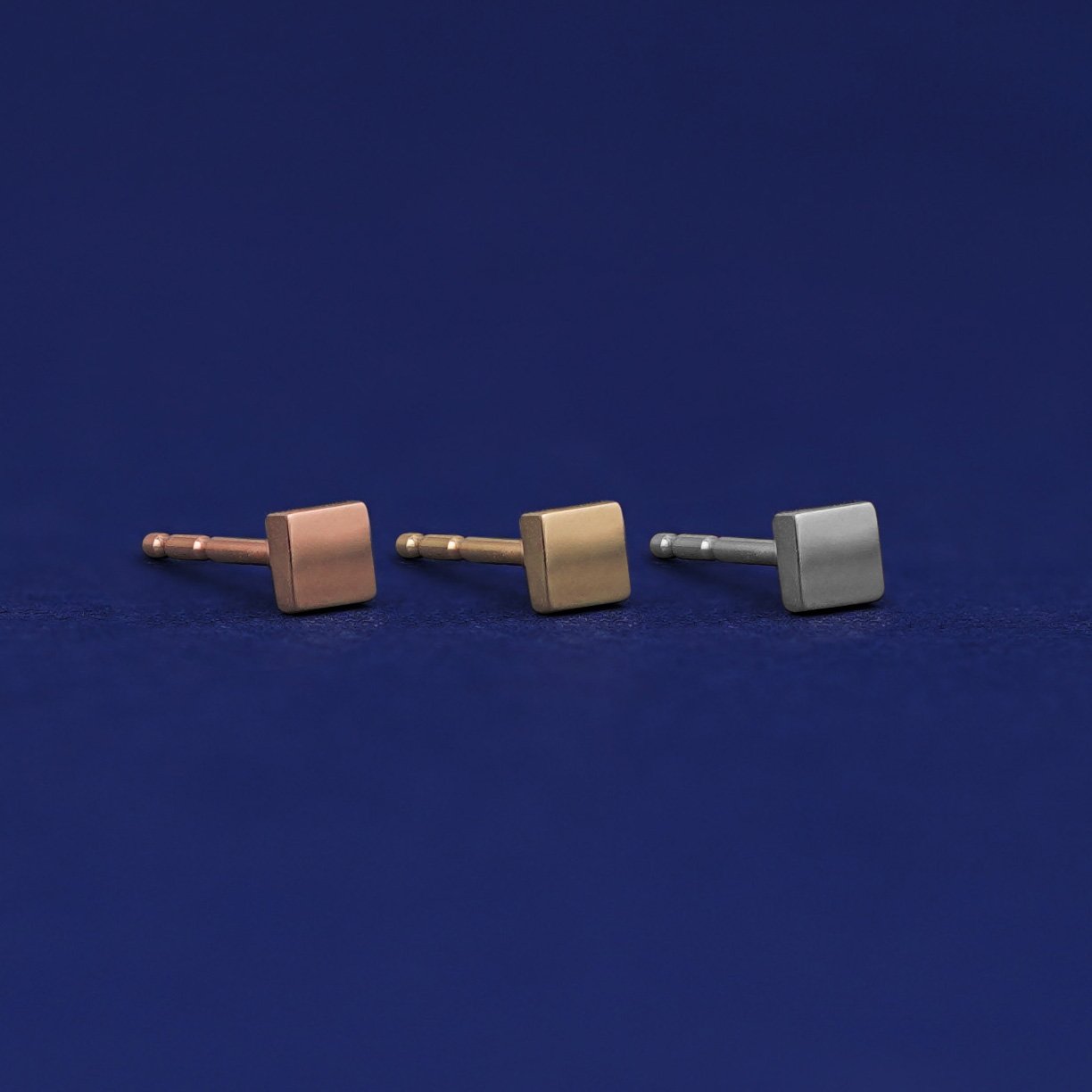 Three versions of the Tiny Square Earring shown in options of rose, yellow, and white gold