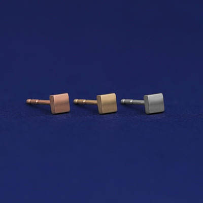 Three versions of the Tiny Square Earring shown in options of rose, yellow, and white gold