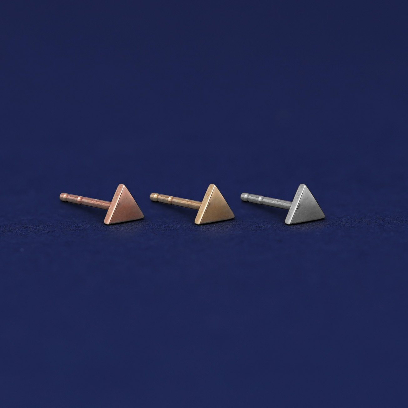 Three versions of the Triangle Earring shown in options of rose, yellow, and white gold