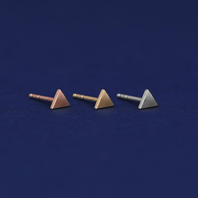Three versions of the Triangle Earring shown in options of rose, yellow, and white gold