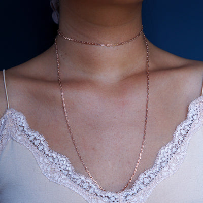 Close up view of a model wearing a 14k rose gold Wrap Necklace doubled as a choker necklace with a long layer