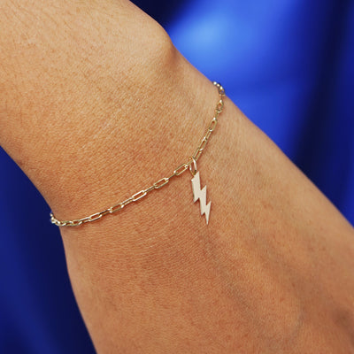 Close up view of a model's wrist wearing a yellow gold Lightning Bolt Charm on a Butch Chain Bracelet