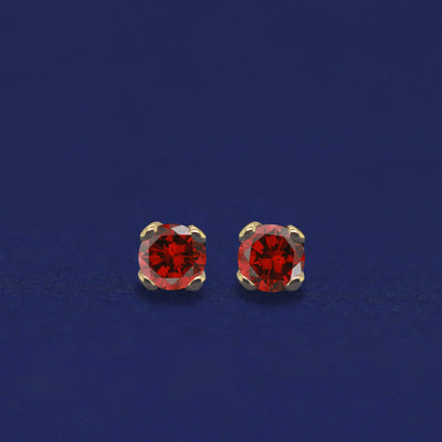 A pair of 14 karat gold studs earrings with 2 millimeter round garnets