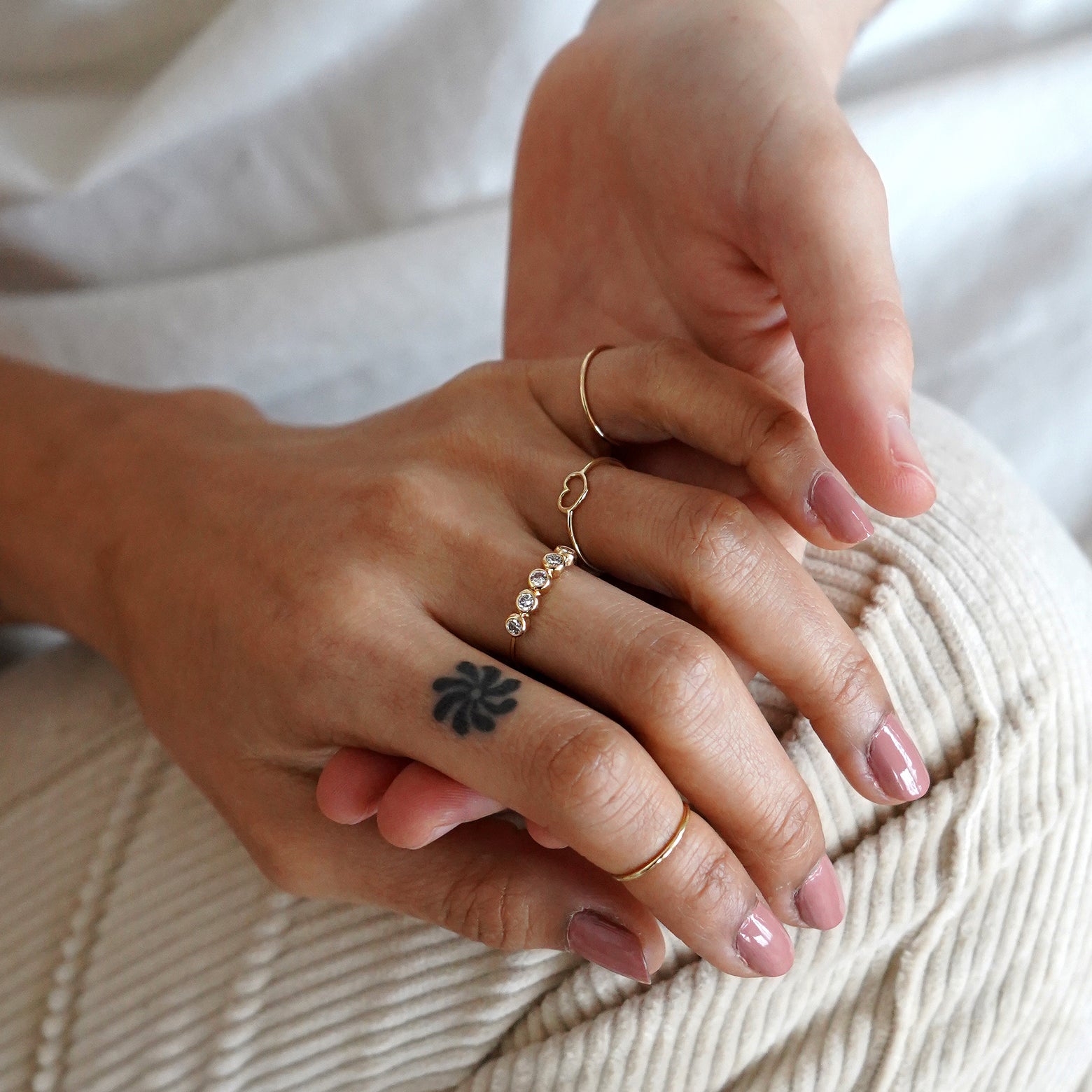 two models holding hands, one model is wearing a 5 diamonds ring, a heart ring and a line ring