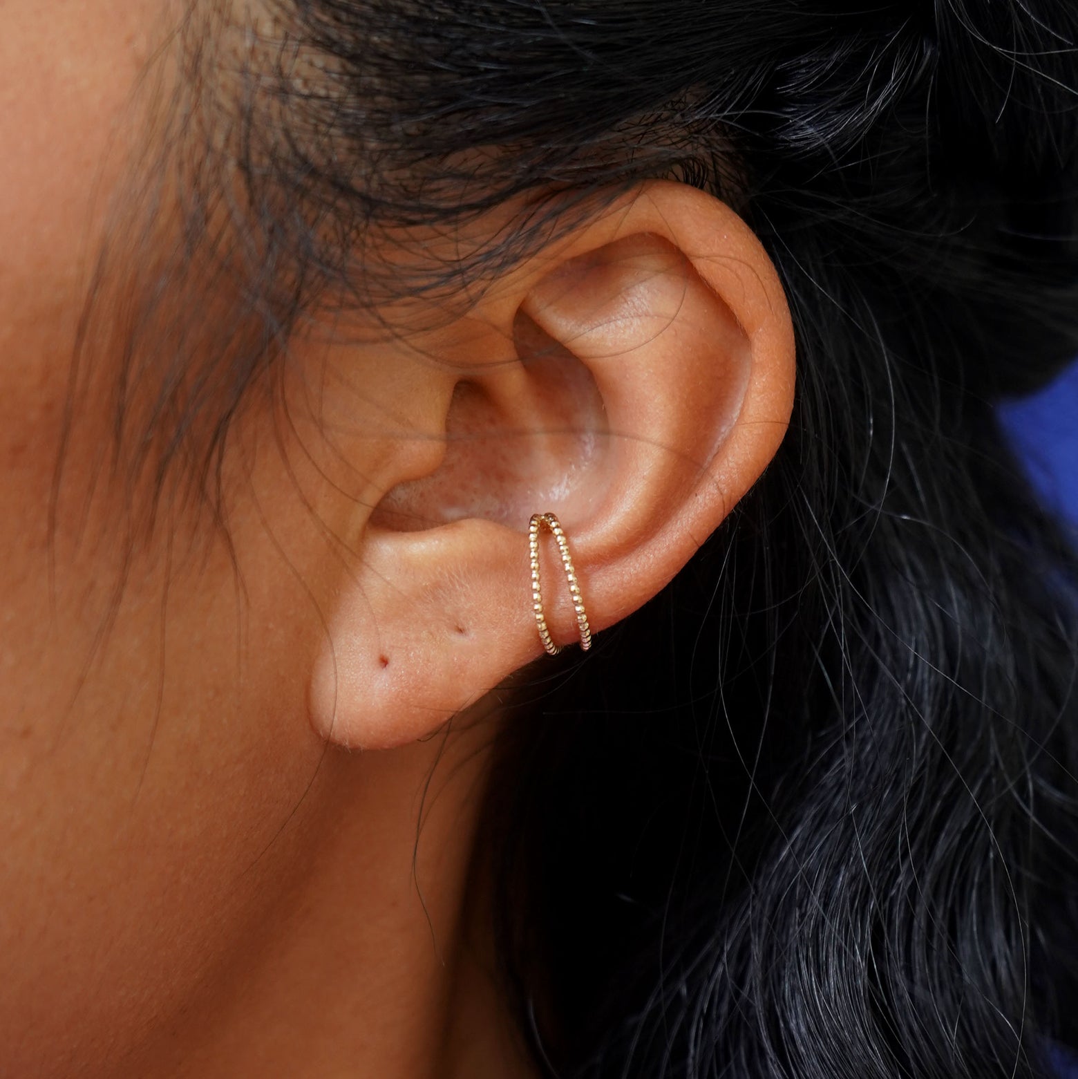 Close up view of a model's ear wearing a yellow gold Bead Cuff